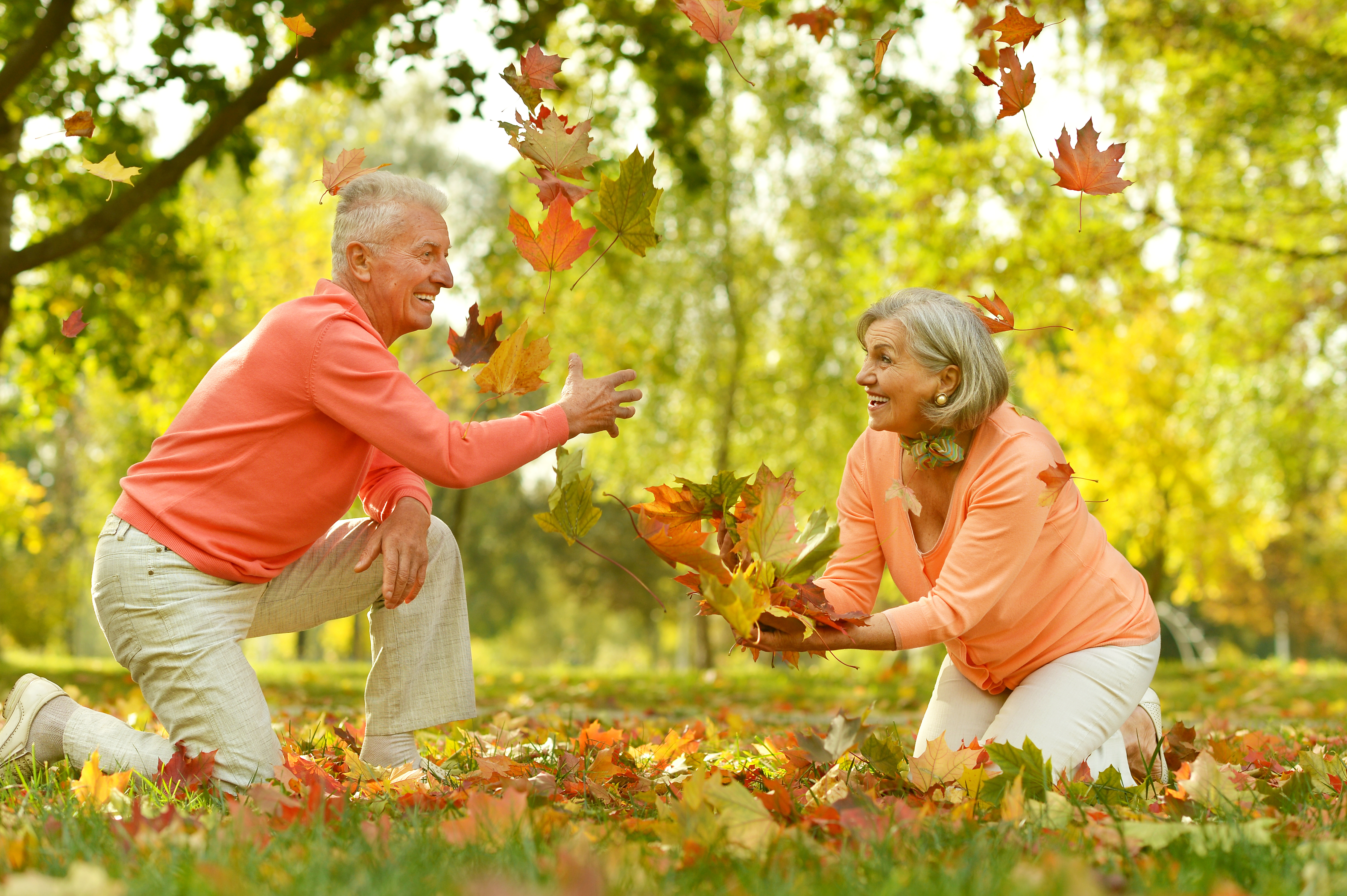 Happy Mature couple play with leaves in autumn park